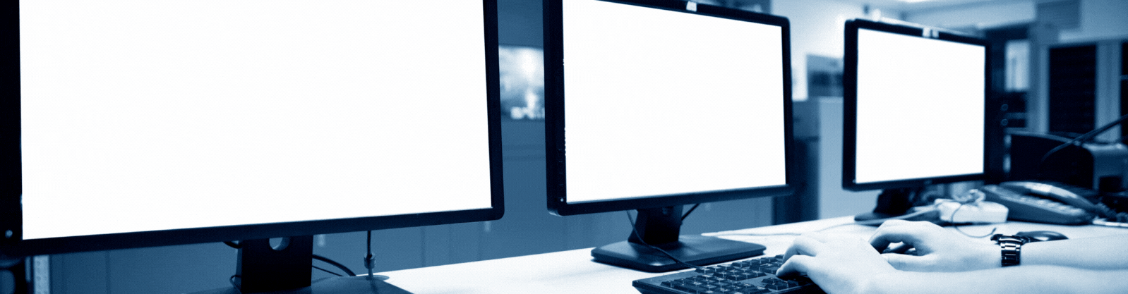 Drei PC-Arbeitsplätze in einer Reihe. Am Bildschirm des mittleren PC-Arbeitsplatzes steht geschrieben: PowerShell Schulung online oder in Präsenz. Das Bild dient als Beitragsbild für die Schulungsdienstleistung in PowerShell